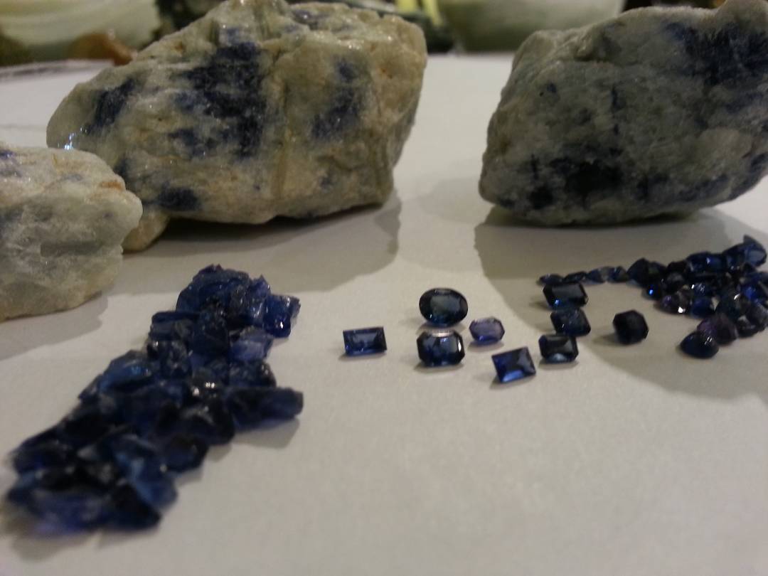 Blue rough and faceted stones displayed beside natural matrix rock