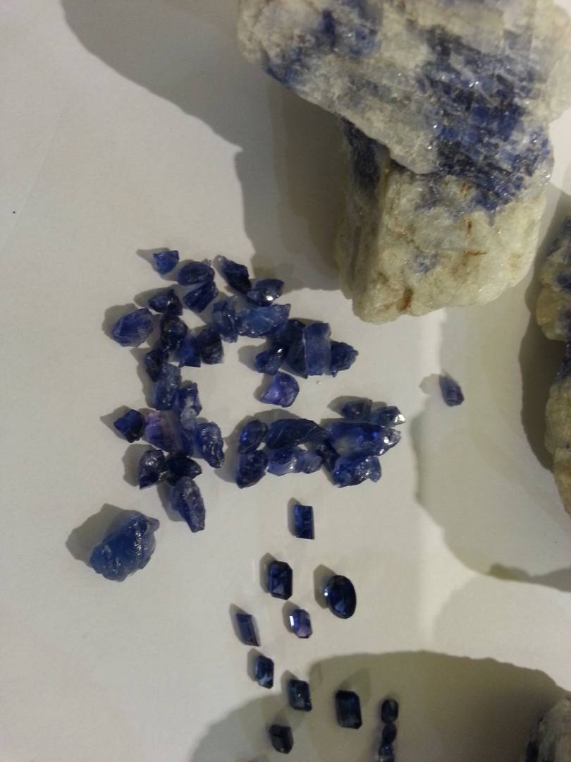 Blue rough stones and faceted samples arranged with matrix rock