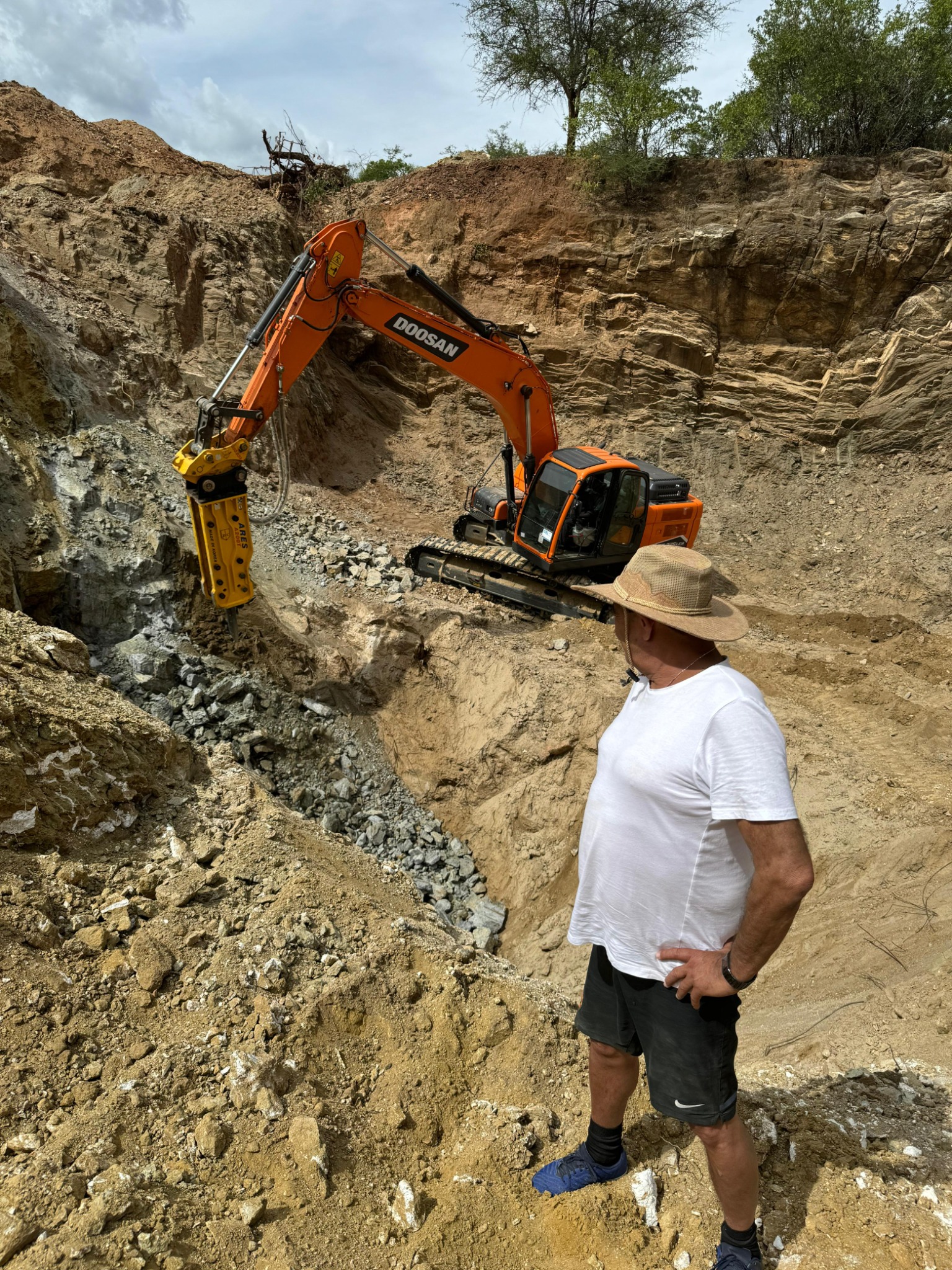 Excavator working against the exposed rock face