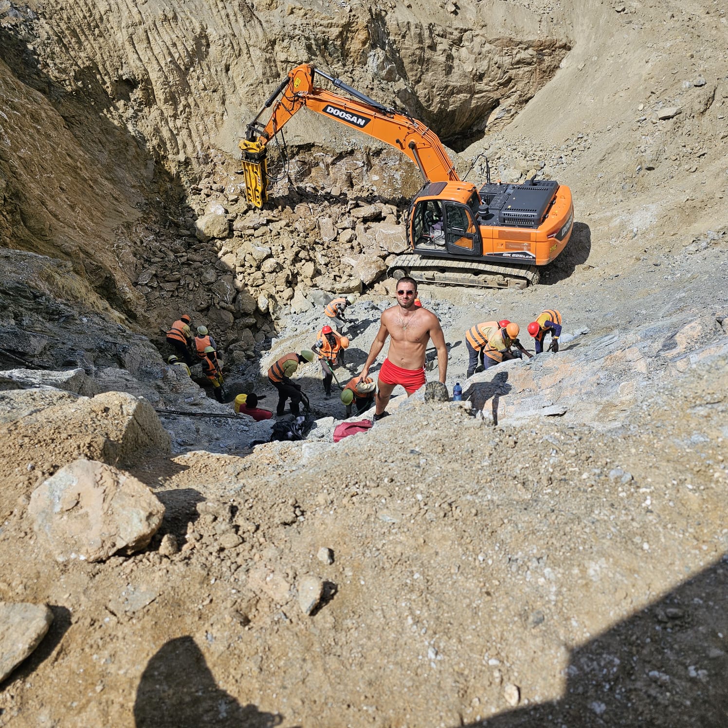 Mining team working below an excavator in an open excavation