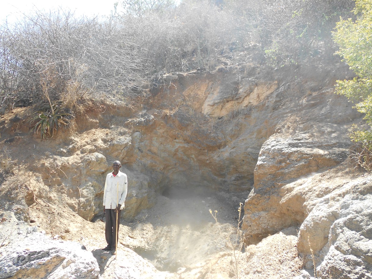Field worker standing inside an open rock excavation