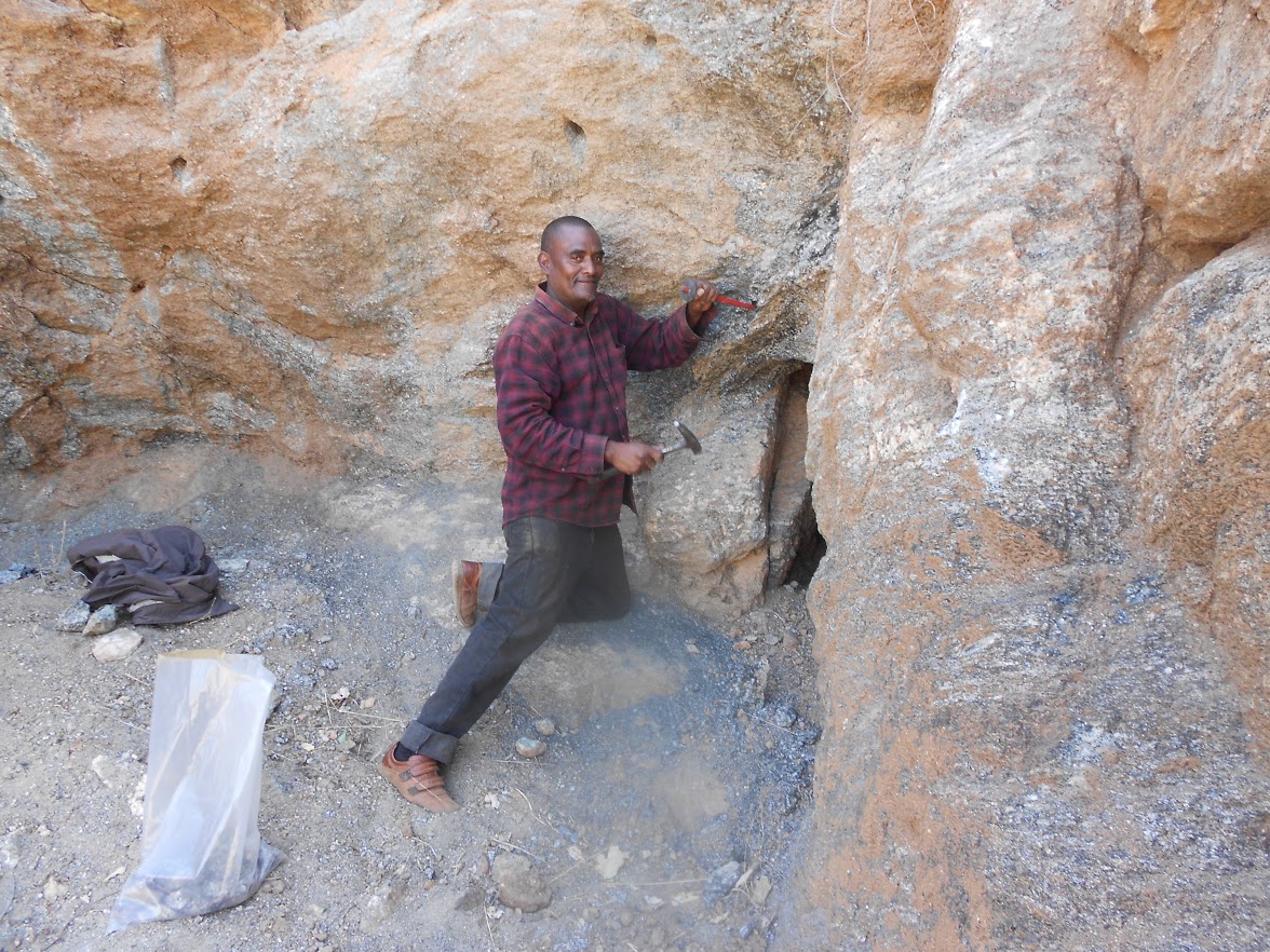 Field worker using hand tools at an exposed rock face